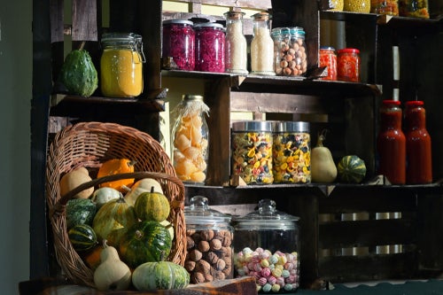 Vegetables and jars of fermented food stacked on cupboard shelves