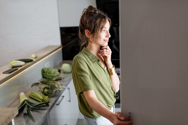Young brunette Caucasian woman looking into the fridge in the kitchen