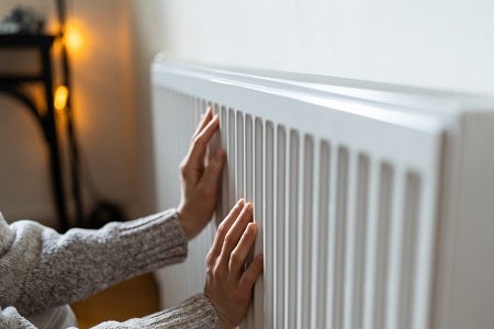 Woman warming her hands on a radiator