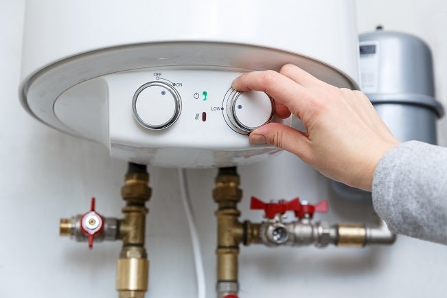 Cropped shot of a female hand changing the settings on a boilers thermostat for electric water