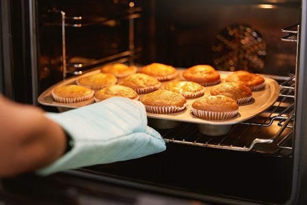 Hand placing muffins into the oven