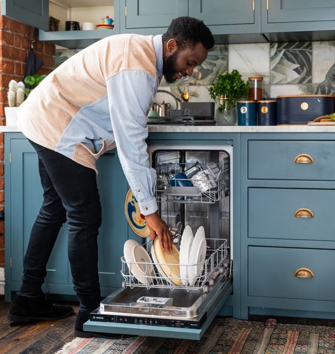 Young black male homeowner loading their dishwasher in the kitchen
