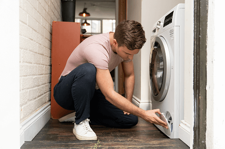 Man crouching by washing machine